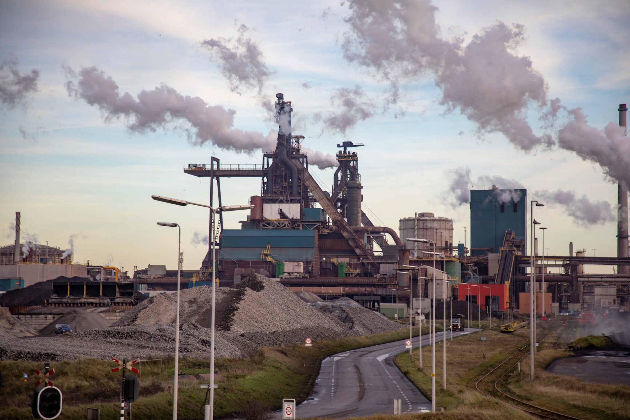 Wijk aan Zee - Nederland, provincie Noord-Holland, stad IJmuiden, gemeente Velsen: op het fabrieksterrein, industrieterrein van de staalfabriek Tata Steel Europa, voormalige Koninklijke Nederlandse Hoogovens en staalfabrieken, KNHS en Corus. Deze staalproducent is een Indiaas-Brits-Nederlandse multinational die staal produceert door ijzererts en koolstof te verhitten, zodat via chemische reacties ijzer ontstaat. De koolstof, samen met zuurstof, dient ook als brandstof voor het verhitten. Bij de staalproductie wordt veel energie gebruikt en ontstaat CO2-uitstoot met alle gevolgen voor het milieu en klimaat. Het industrieterrein van Tata Steel in IJmuiden. Foto: Michel van Bergen.