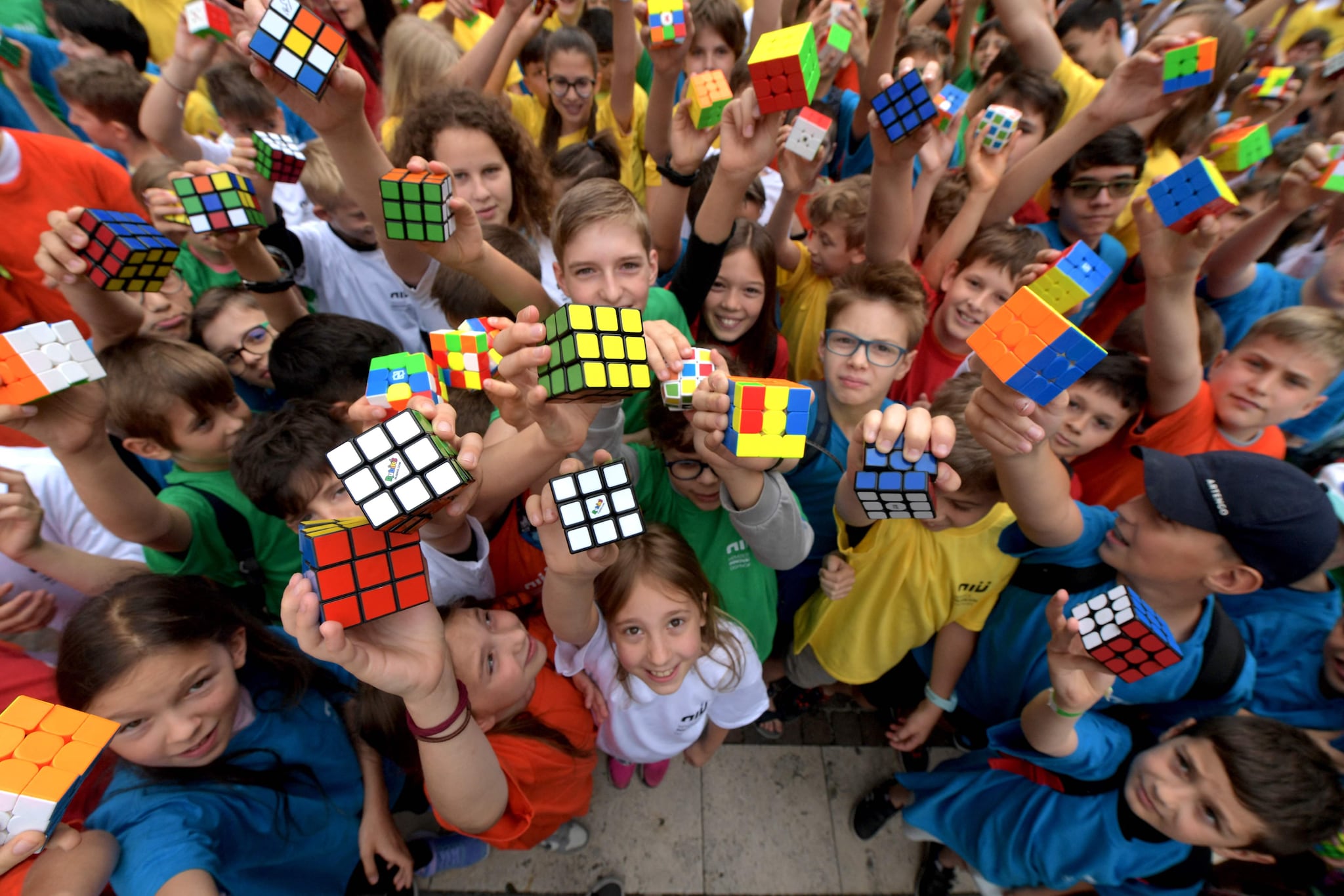 TOPSHOT - Hungarian pupils pose with Rubik's Cubes during a flashmob to celebrate the 50th anniversary of Hungarian architect Erno Rubik’s invention, in Budapest on June 12, 2024. In 1974, Hungarian architecture professor Erno Rubik created the first prototype of a movable cube made out of small wooden blocks and held together by a unique mechanism. More than 500 million copies of the cult object have been sold -- not counting the myriad of counterfeits. Rubik's Cube has remained one of the world's top-selling puzzle games, with more than 43 quintillion -- a quintillion being a billion trillion -- ways of solving it. (Photo by Ferenc ISZA / AFP) Rubik’s Cube: wie heeft er géén? Foto: AFP