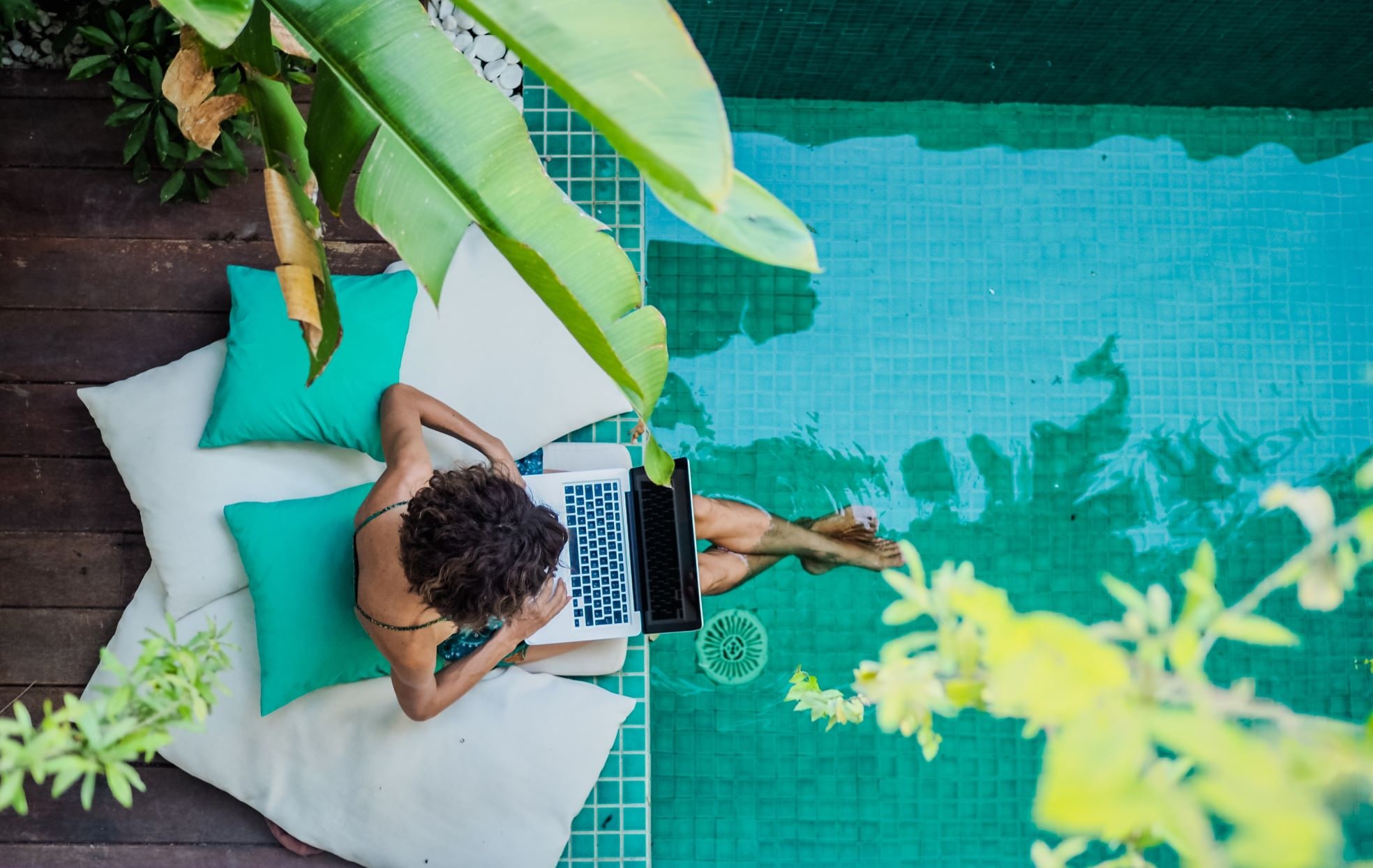 Expat met laptop bij zwembad. Shutterstock