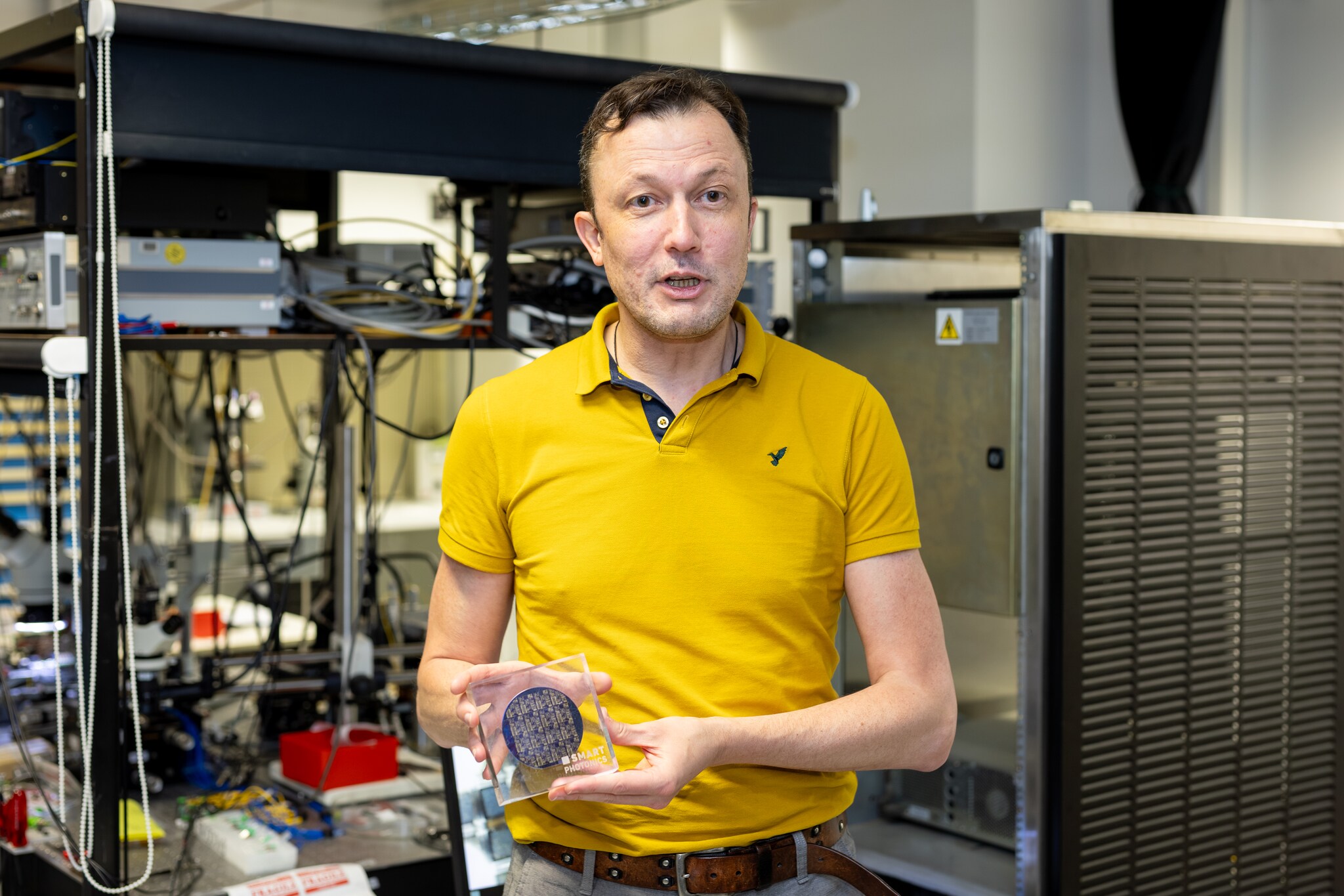 Hoogleraar Martijn Heck van de TU/e toont een wafer met een combinatie van fotonische chips en de gangbare halfgeleiderchips. Foto: Rien Boonstoppel/TU/e