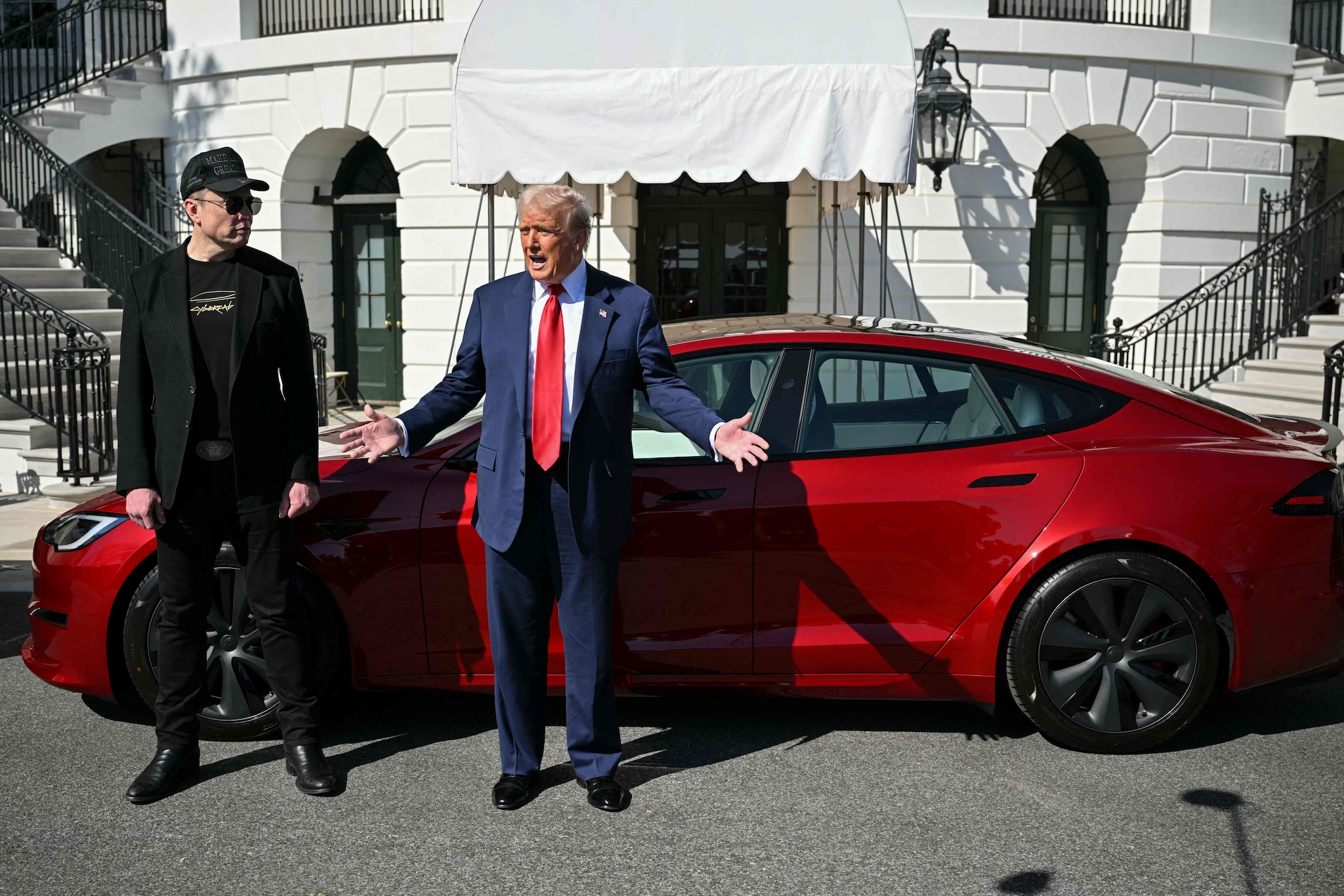 (FILES) US President Donald Trump and Tesla CEO Elon Musk speak to the press as they stand next to a Tesla vehicle on the South Portico of the White House on March 11, 2025 in Washington, DC. Tesla reported another drop in quarterly profits July 23, 2025 on lower auto sales amid intensifying electric vehicle competition and lingering backlash over CEO Elon Musk's involvement in US politics. (Photo by Mandel NGAN / AFP) Juli 2023. Omdat het kan. Elon Musk doet Donald Trump een Tesla kado, bij het Witte Huis. Foto: AFP.