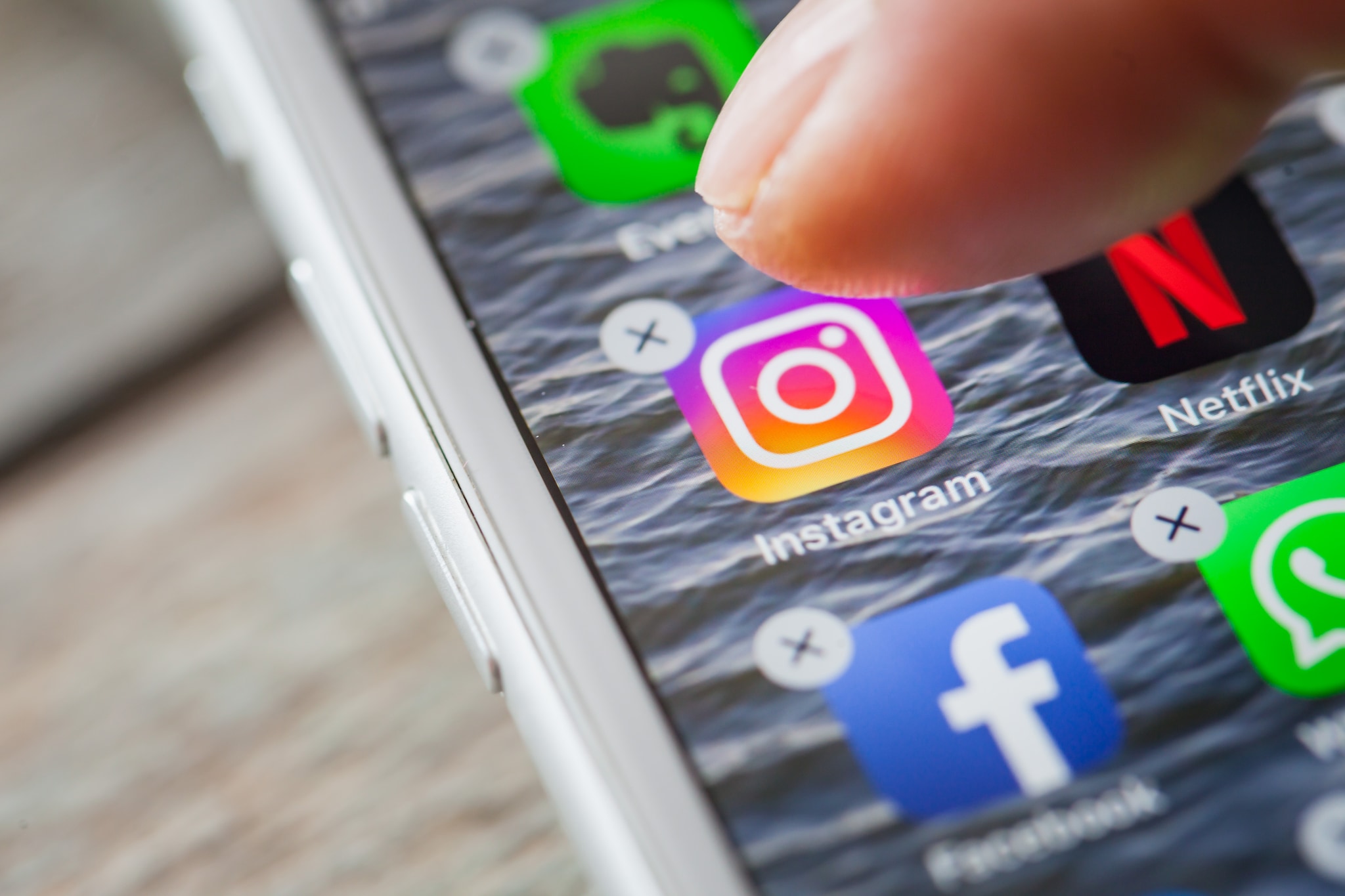 BERLIN, GERMANY - JUNE 6, 2018: Close up to finger deleting the Instagram on the screen of an iPhone 7 Plus with personalized background. De app verlaten of niet? Foto: MichaelJayBerlin/Shutterstock
