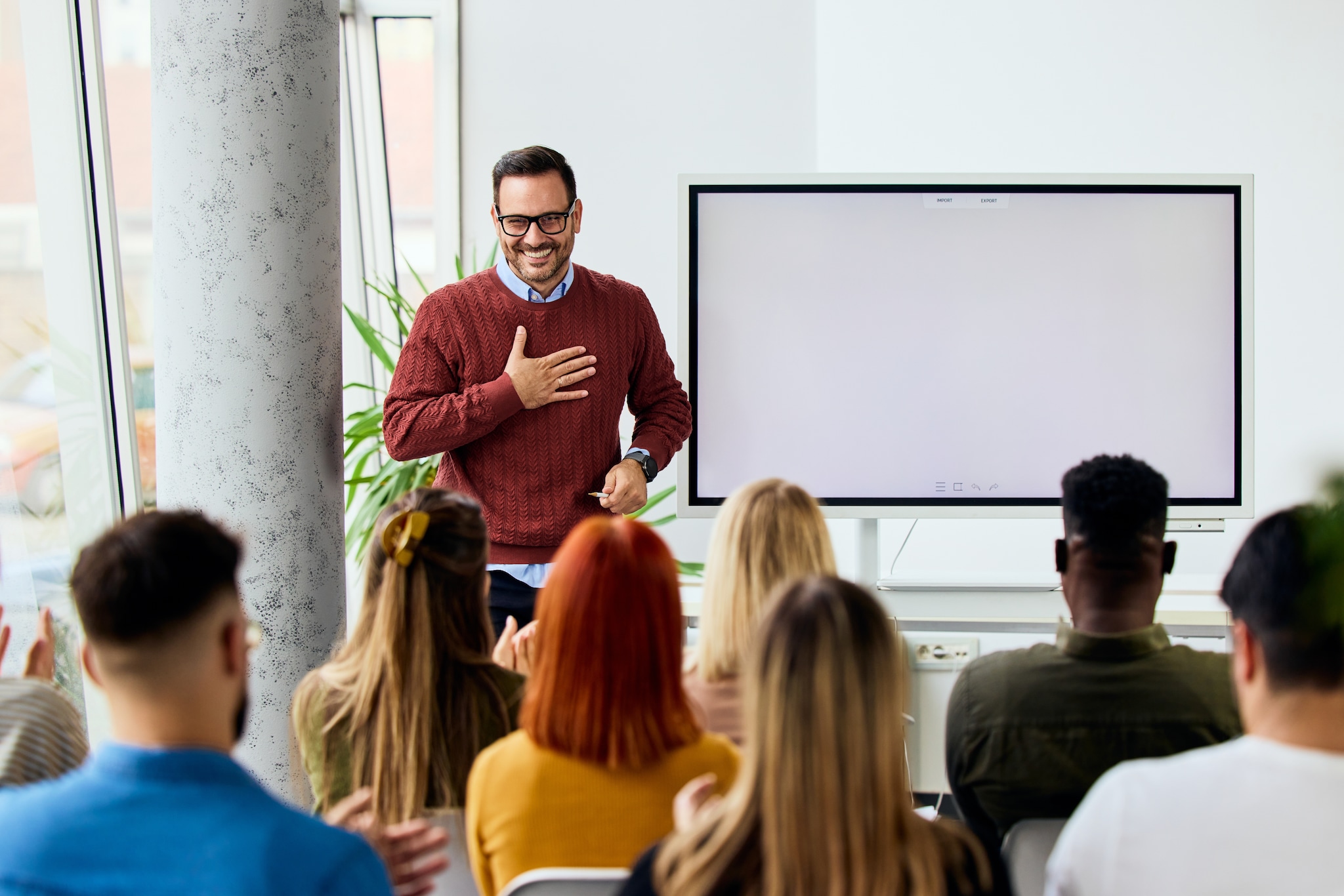 Man in casual attire presenting to an attentive audience in a bright office ‘Jezelf zijn’ in leiderschap, goed idee of niet? Foto: Branislav Nenin/Shutterstock.