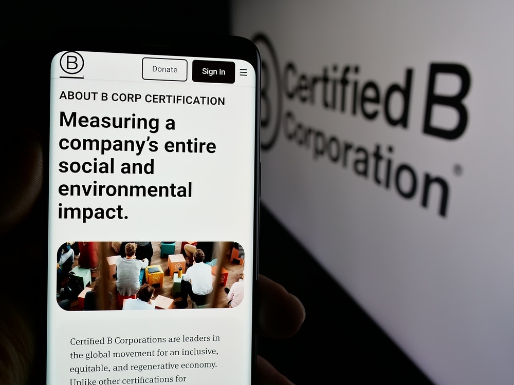 Stuttgart, Germany - 10-10-2024: Person holding cellphone with web page of certification organization B Corporation (B Corp) on screen with logo. Focus on center of phone display. Unmodified photo. Afbeelding: Shutterstock