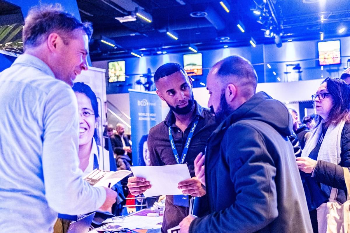 Vluchtelingen bezoeken een banenmarkt in de Johan Cruijff ArenA, georganiseerd om nieuwkomers te helpen bij het vinden van werk. Werkgevers en organisaties bieden informatie en vacatures aan. De markt is gratis en gericht op integratie via werk. Foto: ANP / Hollandse Hoogte / Joris van Gennip Vluchtelingen bezoeken een banenmarkt, georganiseerd om nieuwkomers te helpen bij het vinden van werk. Werkgevers en organisaties bieden informatie en vacatures aan. Foto: ANP.