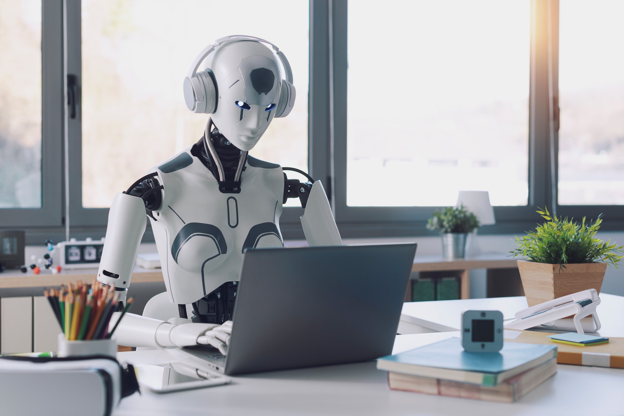 A humanoid robot works in an office on a laptop to listening Music in  Headphone, showcasing the utility of automation in repetitive and tedious tasks. Getty Images