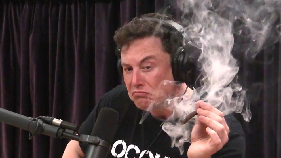 Een blowende Elon Musk tijdens de veelbesproken podcast met Joe Rogan. Afbeelding via YouTube.